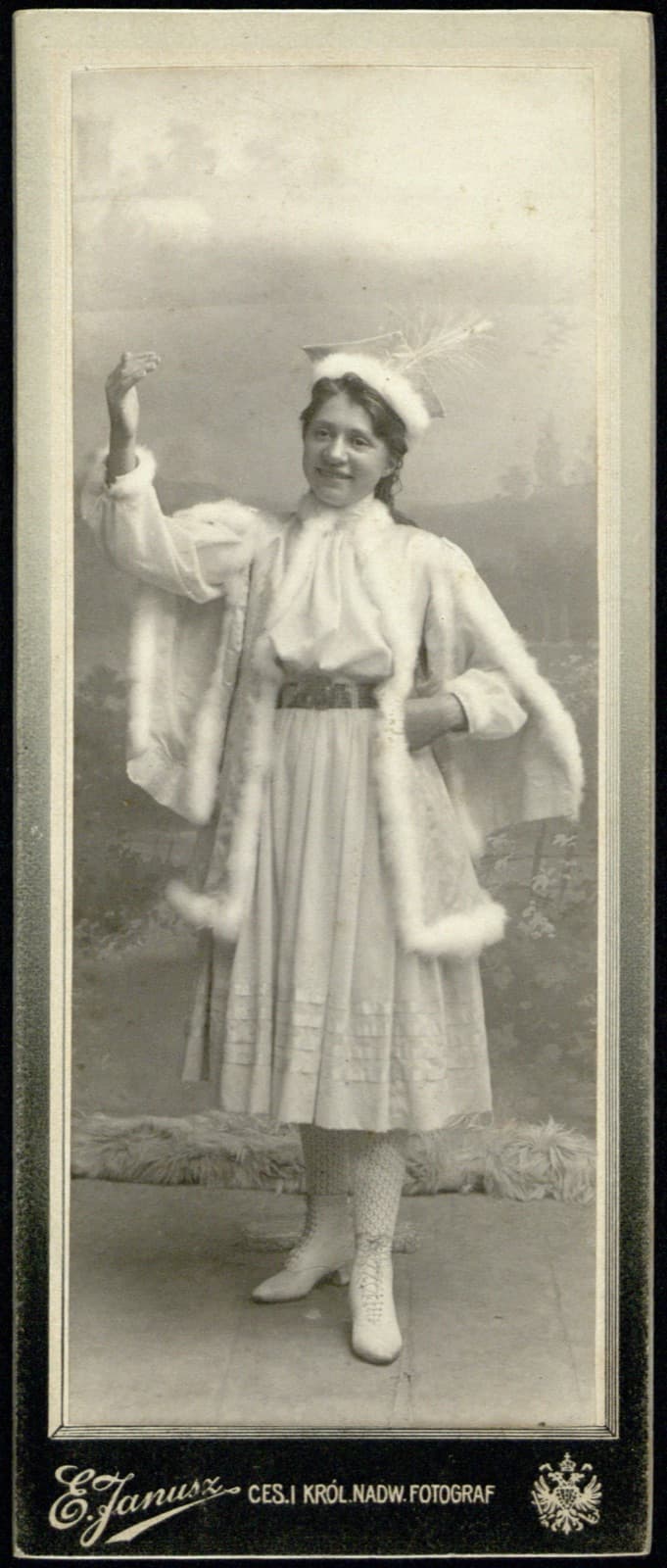 Edward Janusz (Rzeszów) – portret młodej kobiety/dziewczyny w białej pelerynie z futrem i kapeluszu z piórem, poza teatralna (archiwum rodziny Januszów), fotografia (format podłużny)