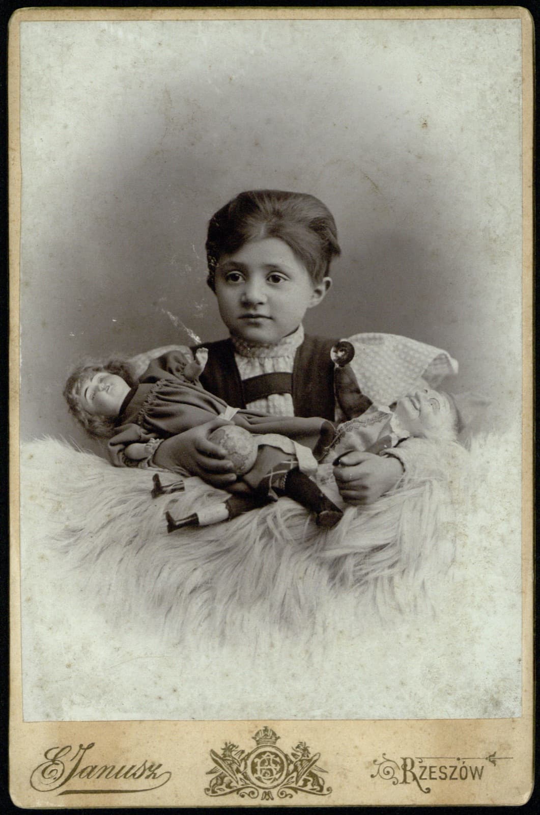 Edward Janusz (Rzeszów) – portret dziecka z dwiema lalkami (album rodzinny Januszów; wczesny nakład – ul. Sandomierska), fotografia gabinetowa [scena rodzajowa]