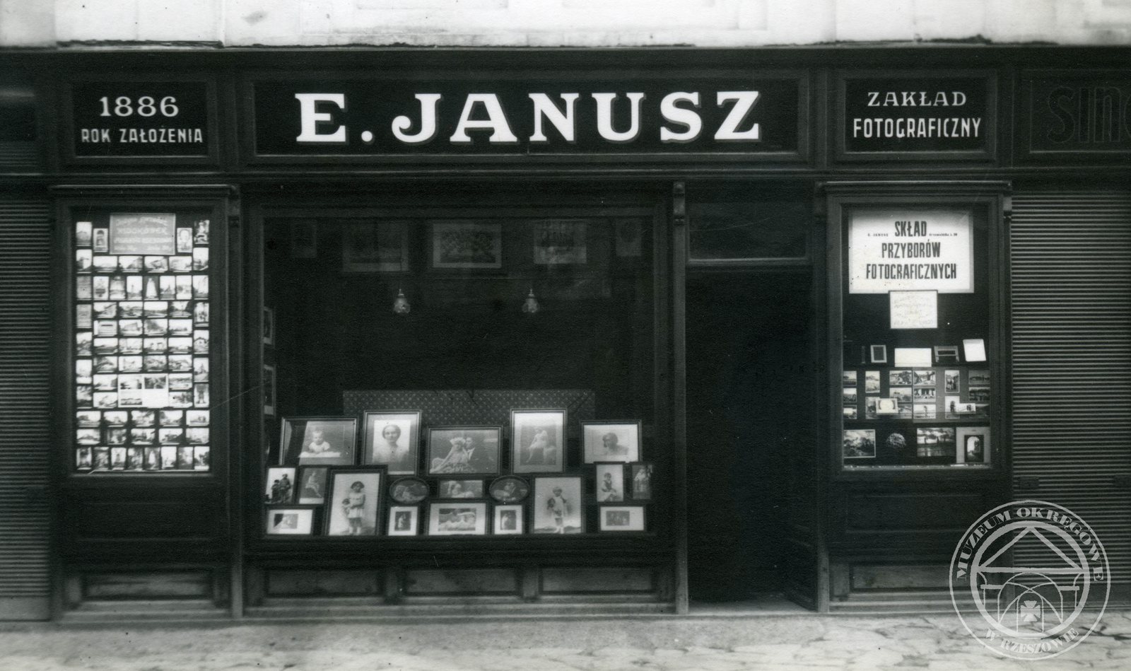 Witryna zakładu fotograficznego E. Janusz przy ulicy w Rzeszowie, pełna wystawionych portretów w ramkach